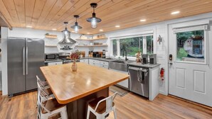 A modern kitchen with a wooden ceiling, stainless steel appliances, and a central island with seating.