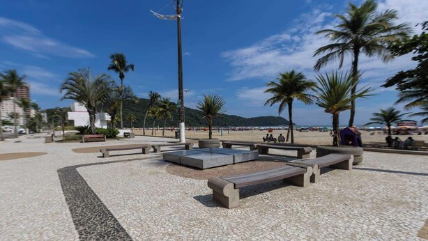 Ein öffentlicher Platz mit Sitzgelegenheiten und einem Strand im Hintergrund.