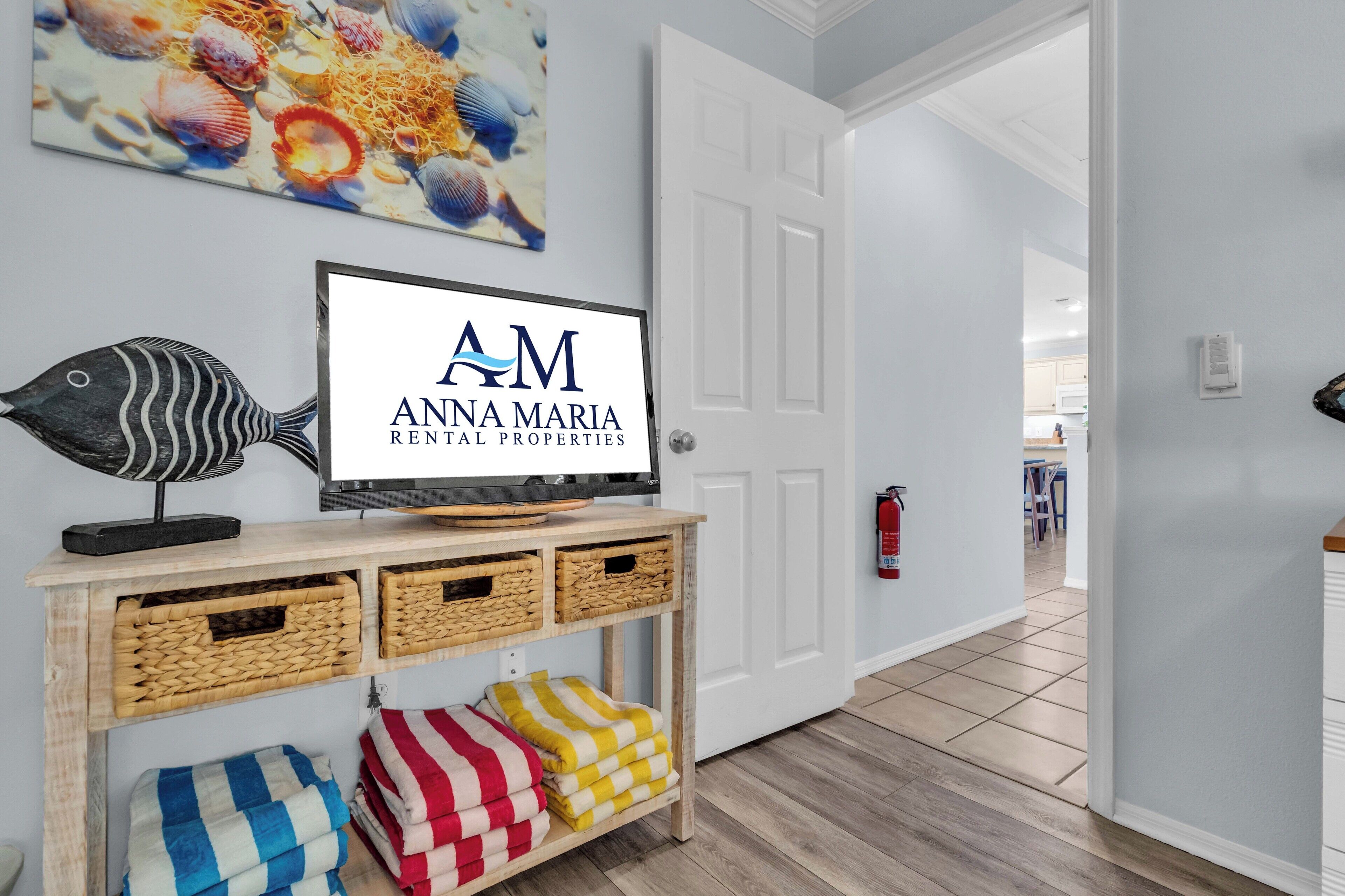 A hallway with a wooden console table displaying a television, baskets, and colorful towels.