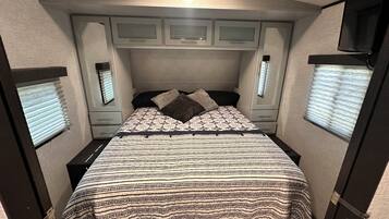 A bedroom with a bed, bedside tables, a wardrobe, and a television.
