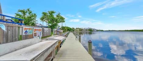 A wooden dock extending into calm water, with a clear sky above.
