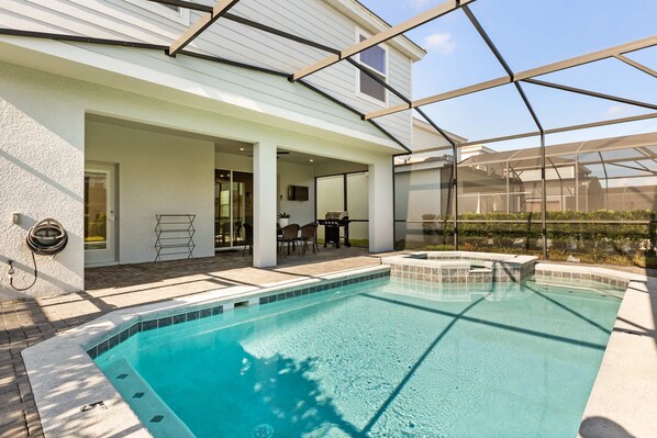 A swimming pool with a glass enclosure, a patio area with chairs, and a covered seating area. - Family Fun Villa w Pool Hot Tub Game Room (Davenport)