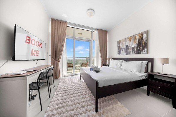 Una habitación de hotel con cama, escritorio, silla y un ventanal con cortinas.