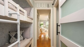 A narrow hallway with bunk beds on one side and a door on the other. - Island Condo for 6 w Communal Pool - Perfect Spot! (Hilton Head Island)