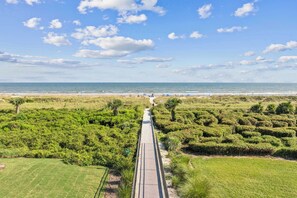 A boardwalk leading to a beach with a clear sky and distant horizon.