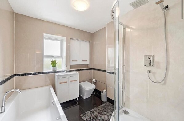A modern bathroom with a bathtub, a shower, and a toilet. - Newark Road (North Hykeham)