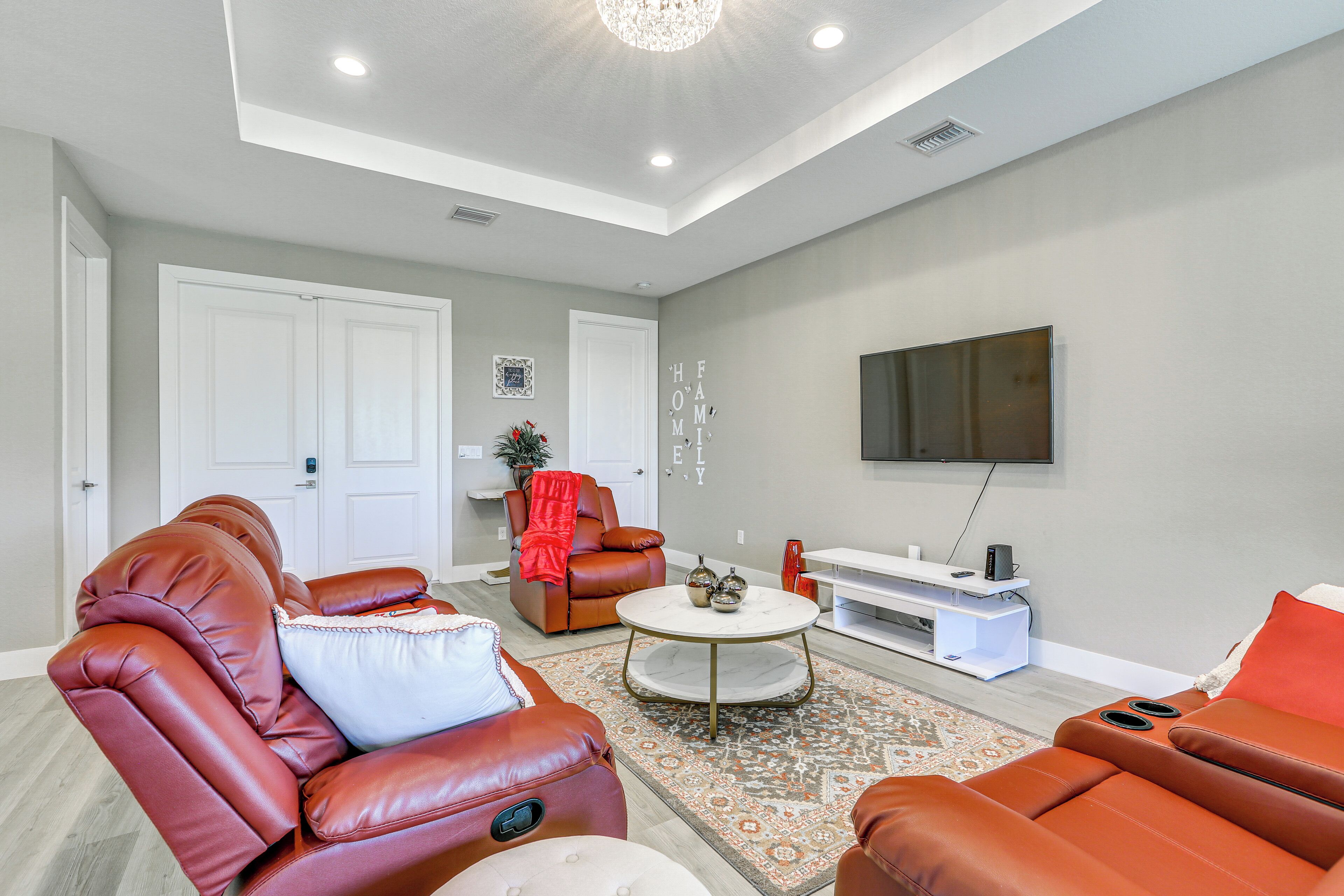 A modern living room with leather sofas, a coffee table, and a flat-screen TV mounted on the wall.