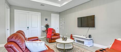 A modern living room with leather sofas, a coffee table, and a flat-screen TV mounted on the wall.