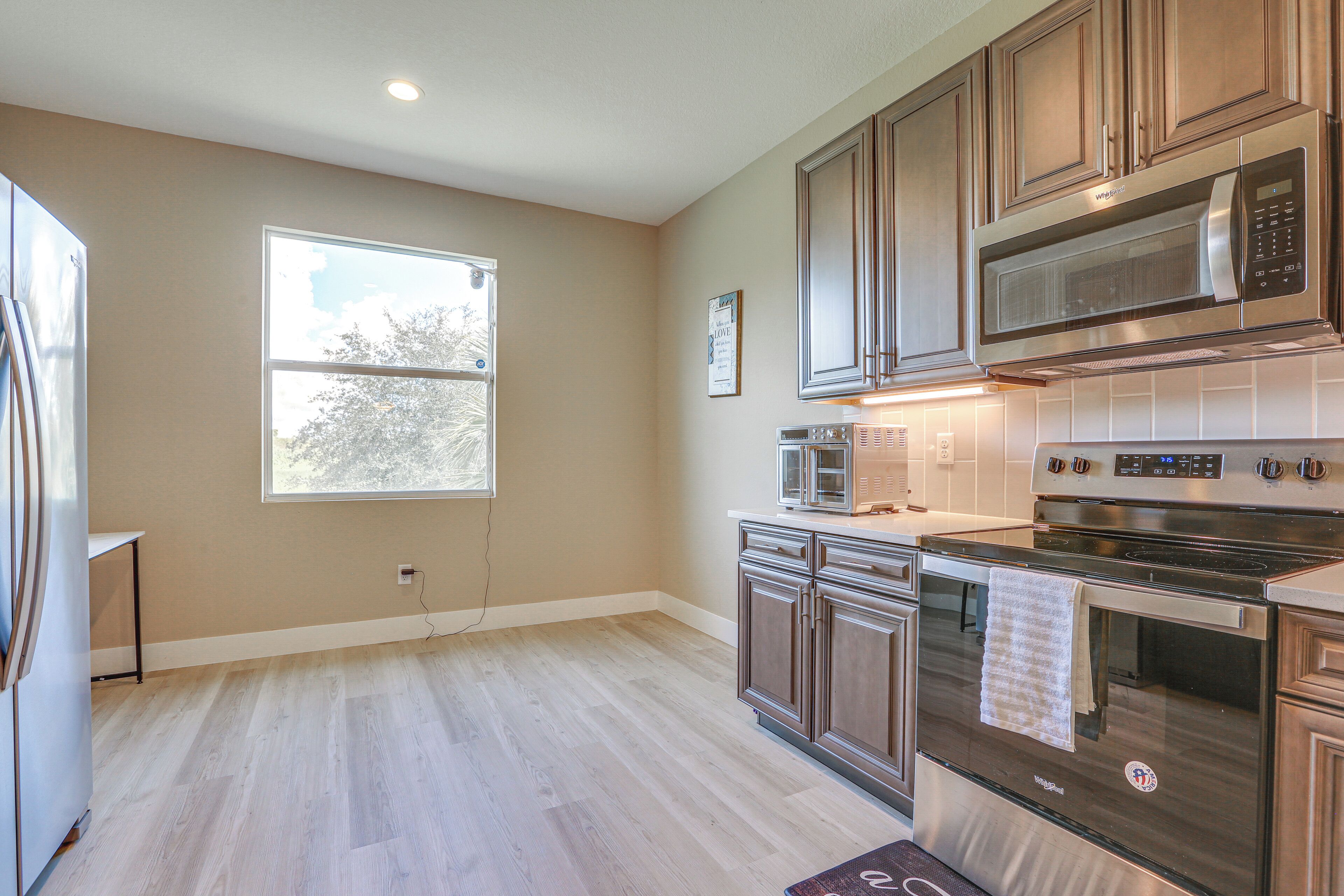 A modern kitchen with wooden cabinets, stainless steel appliances, and a large window providing natural light.