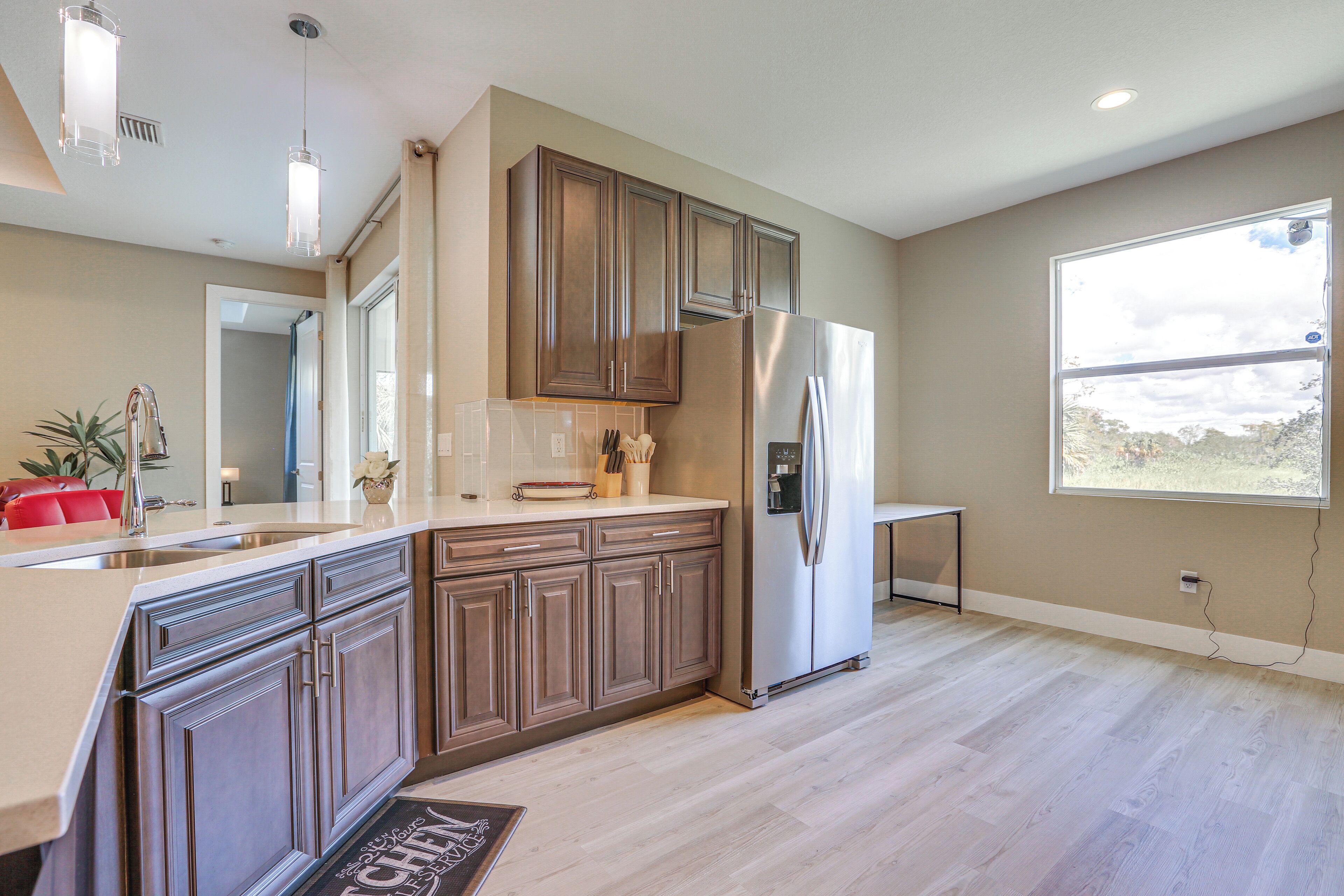 A modern kitchen with wooden cabinets, stainless steel appliances, and a large window providing natural light.