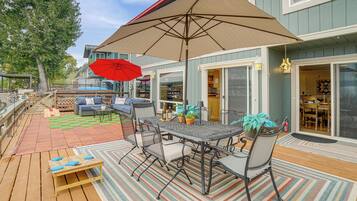 An outdoor patio with a table and chairs, a red umbrella, and a wooden deck.