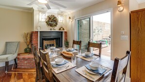 A dining area with a wooden table set for four, a fireplace, and a view of the outdoors.