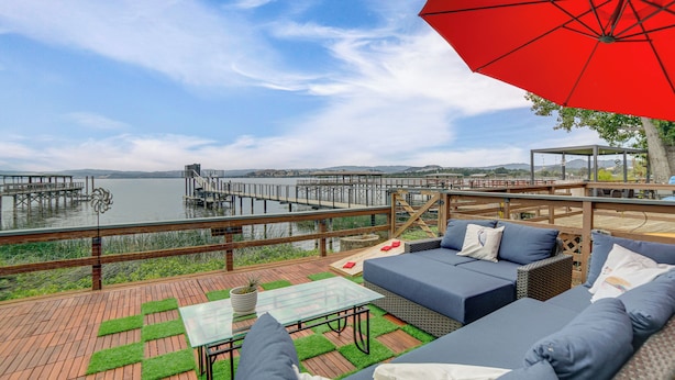 A deck with outdoor furniture, a glass table, and a red umbrella. - Waterfront Clear Lake Home w/ Game Room & Deck! (Upper Lake)