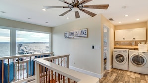 A spacious laundry room with a view of the lake, a ceiling fan, and a sign that reads "GO JUMP IN THE LAKE". - Waterfront Clear Lake Home w/ Game Room & Deck! (Upper Lake)