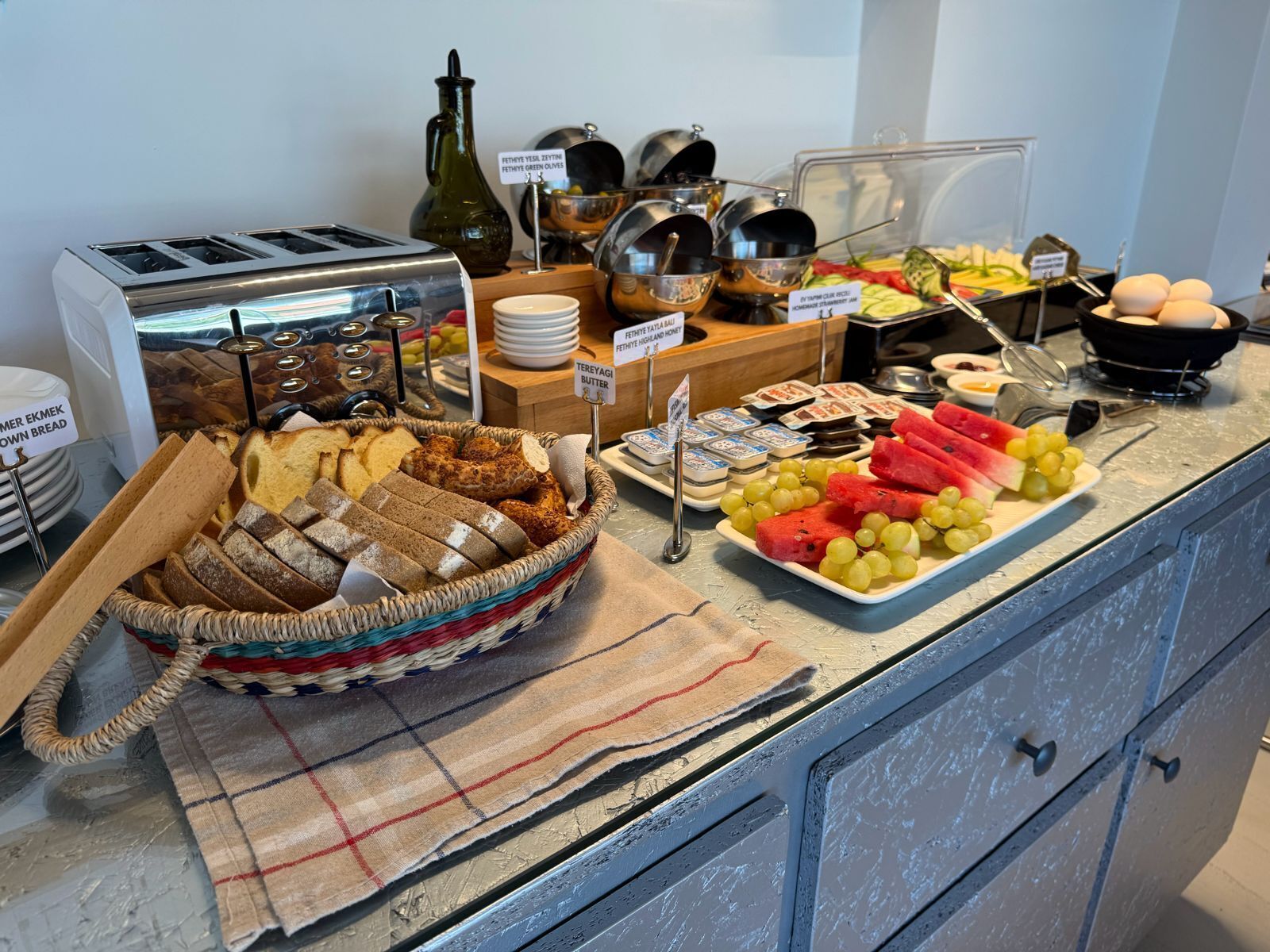 A buffet with various food items, including bread, fruits, and condiments.