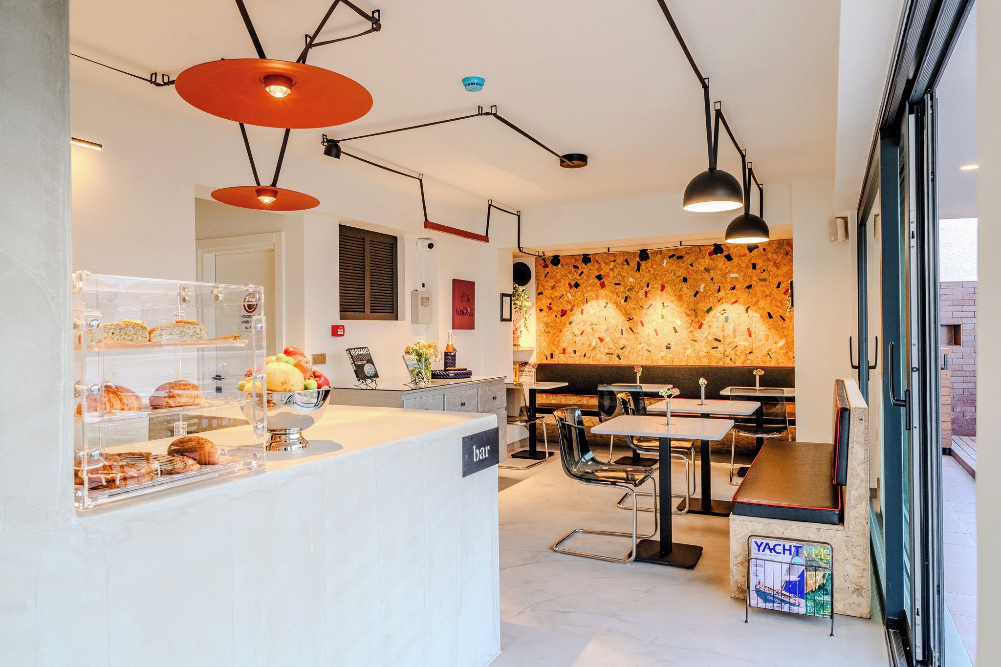 A modern restaurant with a bar area, clear glass display cases with food, and contemporary lighting fixtures.