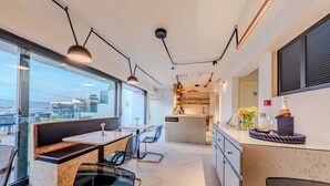 A modern restaurant with a reception desk, seating area, and kitchen visible.