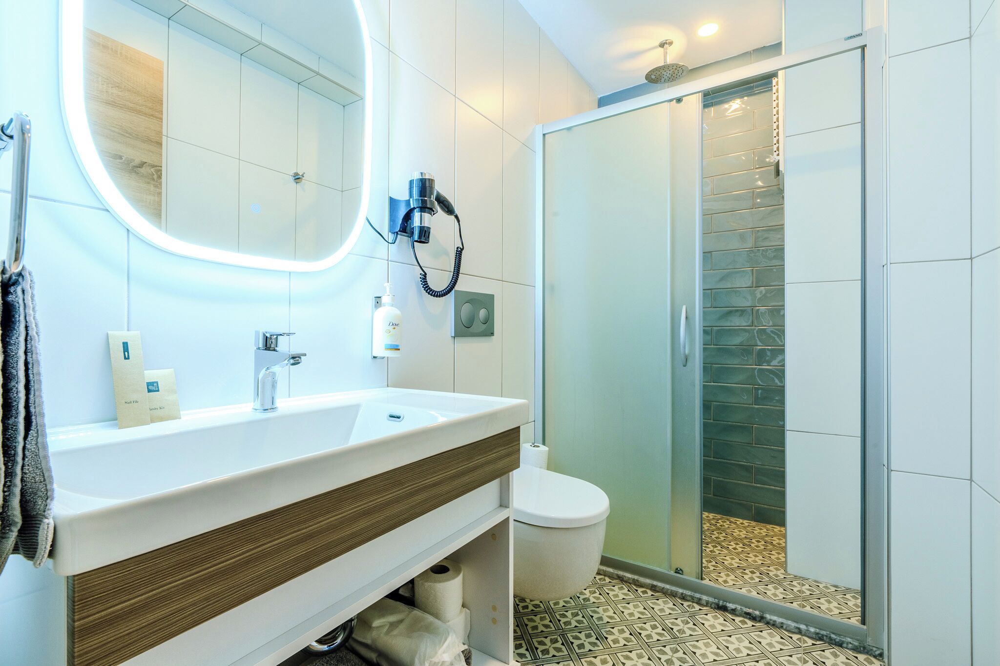 Une salle de bain moderne avec un lavabo blanc, un miroir et une cabine de douche en verre.