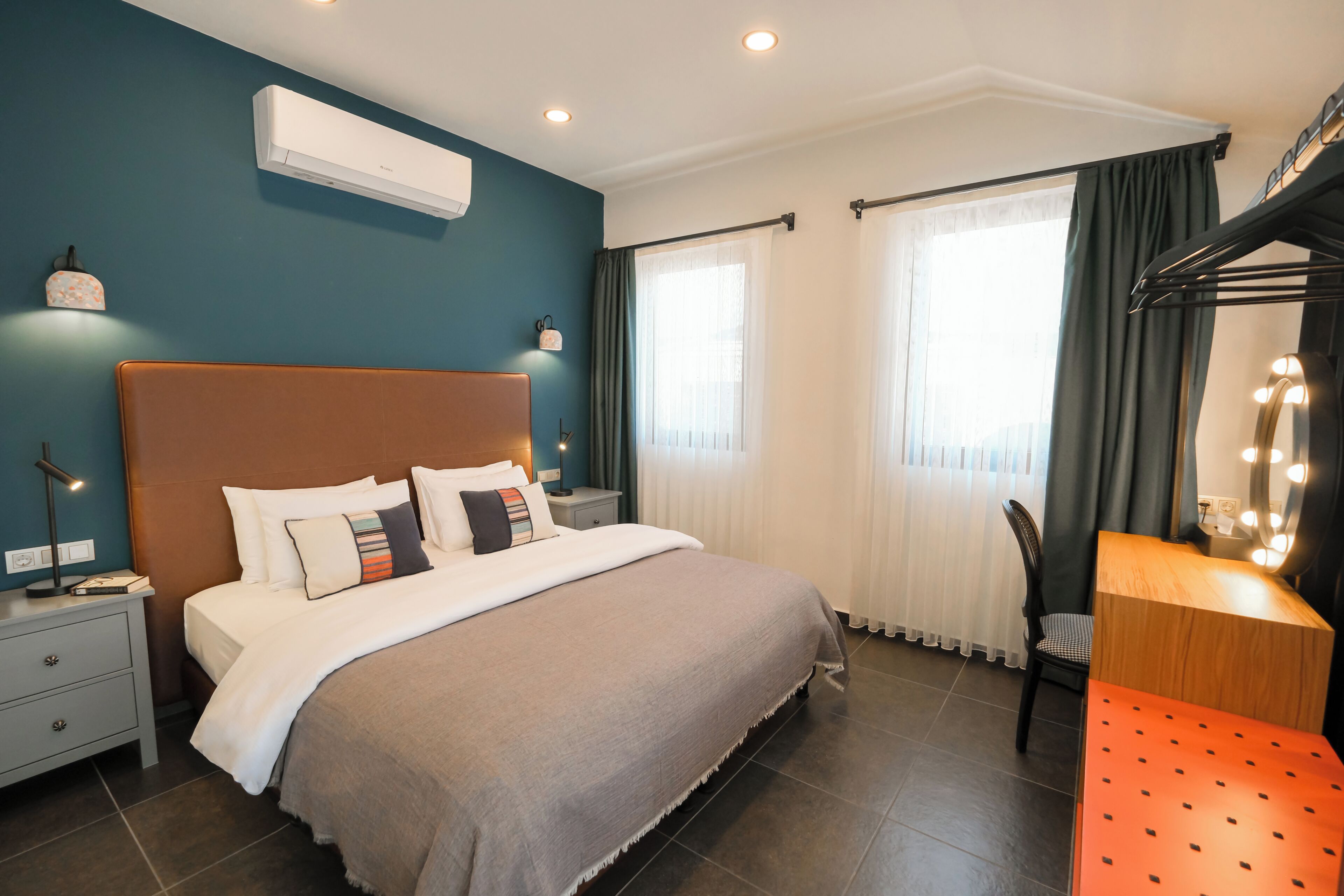 A bedroom with a large bed, bedside tables, a desk with a mirror, and a chair.