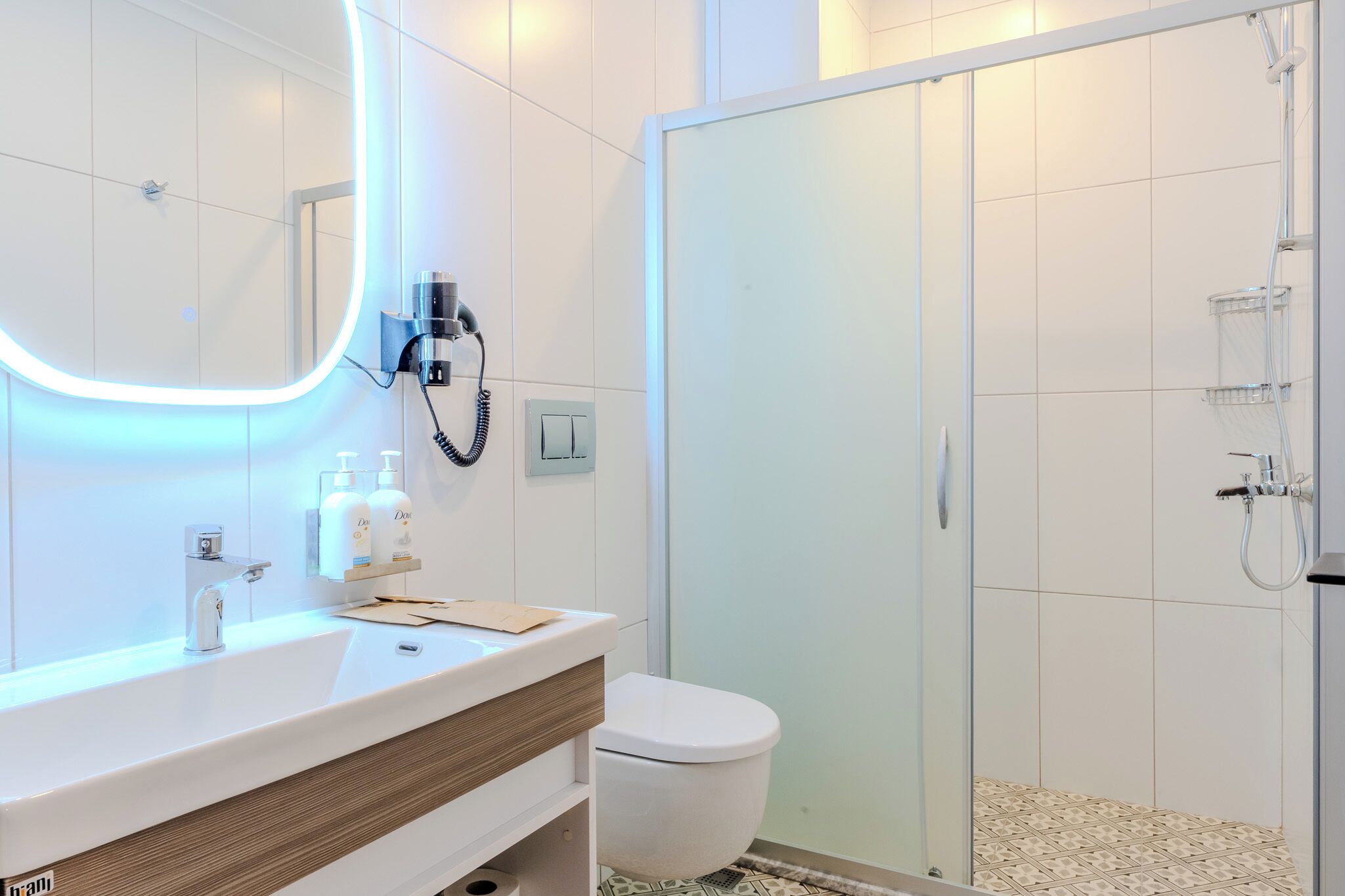 Ein modernes Badezimmer mit großem Spiegel, Waschbecken, Toilette und Duschbereich.