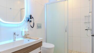 Ein modernes Badezimmer mit großem Spiegel, Waschbecken, Toilette und Duschbereich.