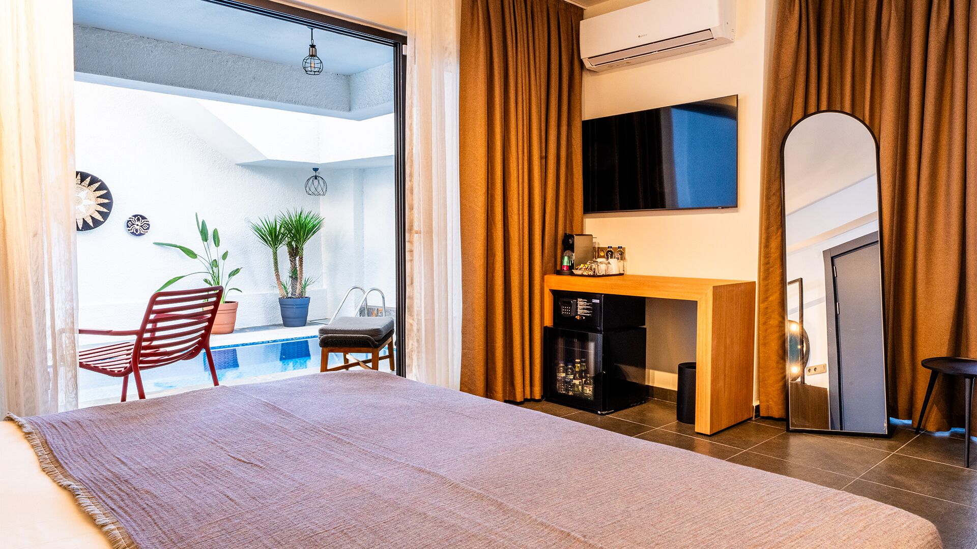 A modern hotel room with a large bed, a small desk, a coffee machine, and a TV.