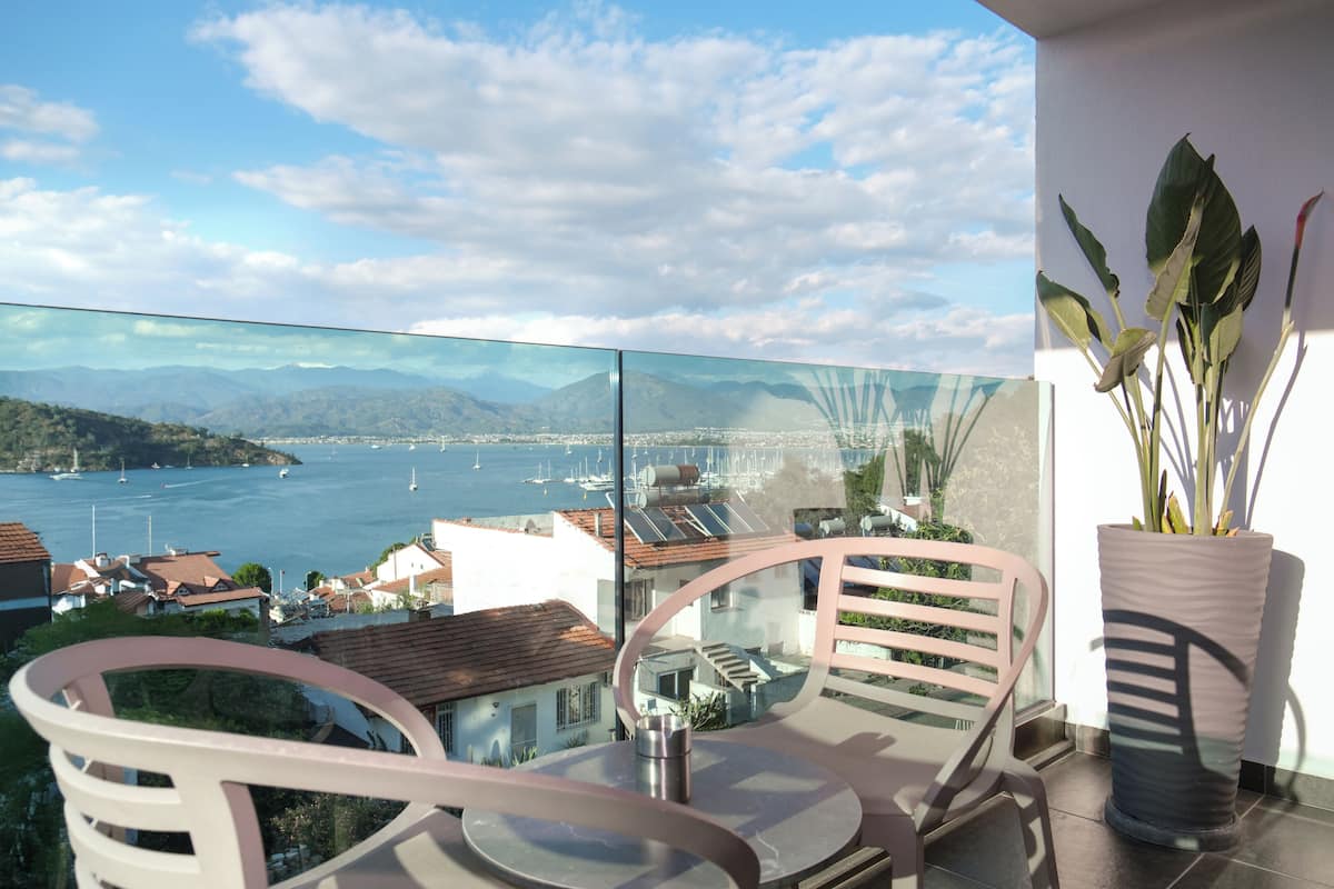 Een balkon met uitzicht op een kustplaats, een stoel, een bloempot en een tafel.