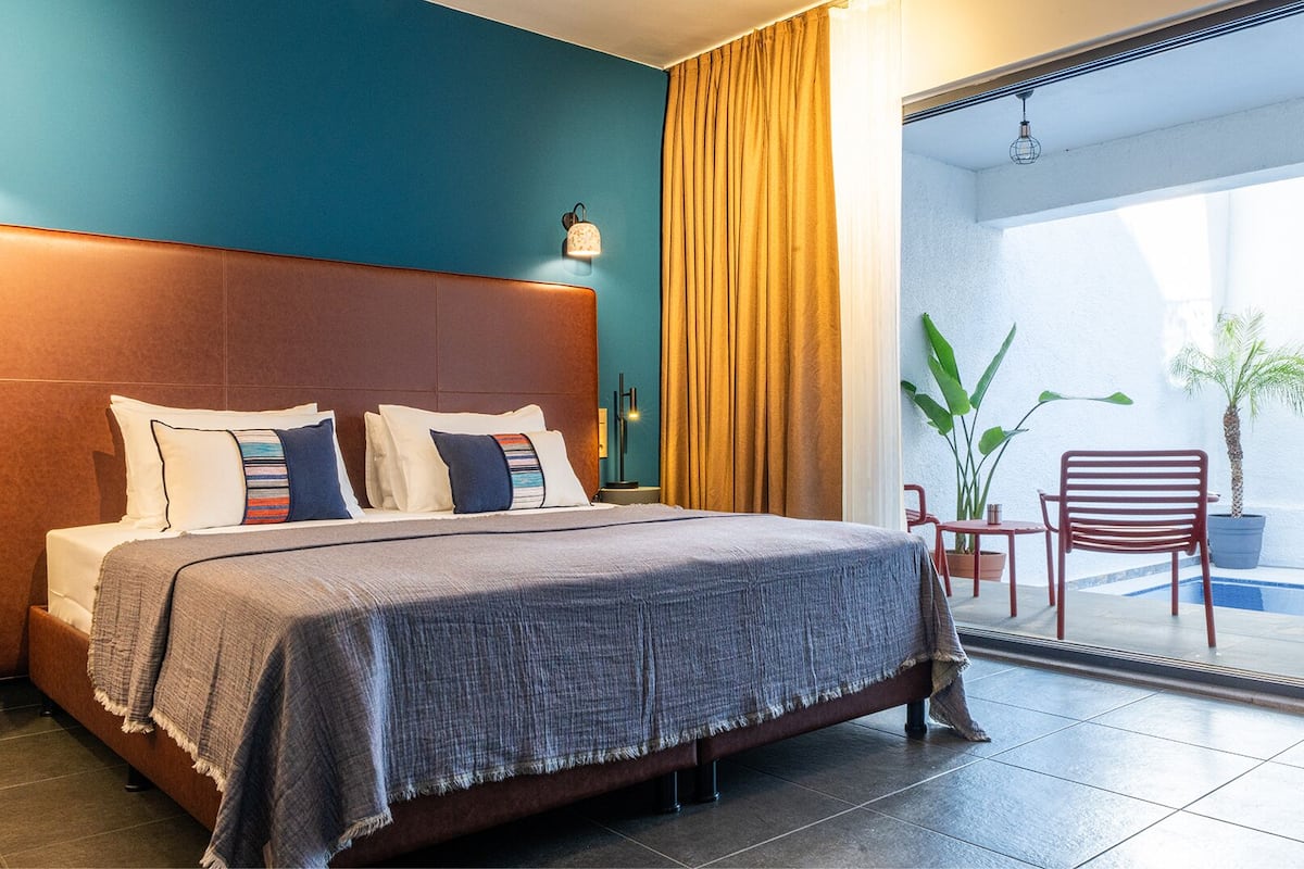 Hotelkamer met een groot bed, een nachtkastje, een lamp, uitzicht op het balkon en een potplant.