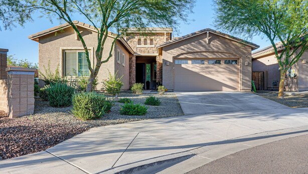 A two-story house with a garage, surrounded by a landscaped garden and trees. - Mtn Views & Private Hot Tub: Buckeye Getaway (Buckeye)