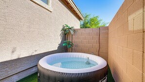 An inflatable hot tub in a backyard with a brick wall, a palm tree, and a house in the background. - Mtn Views & Private Hot Tub: Buckeye Getaway (Buckeye)