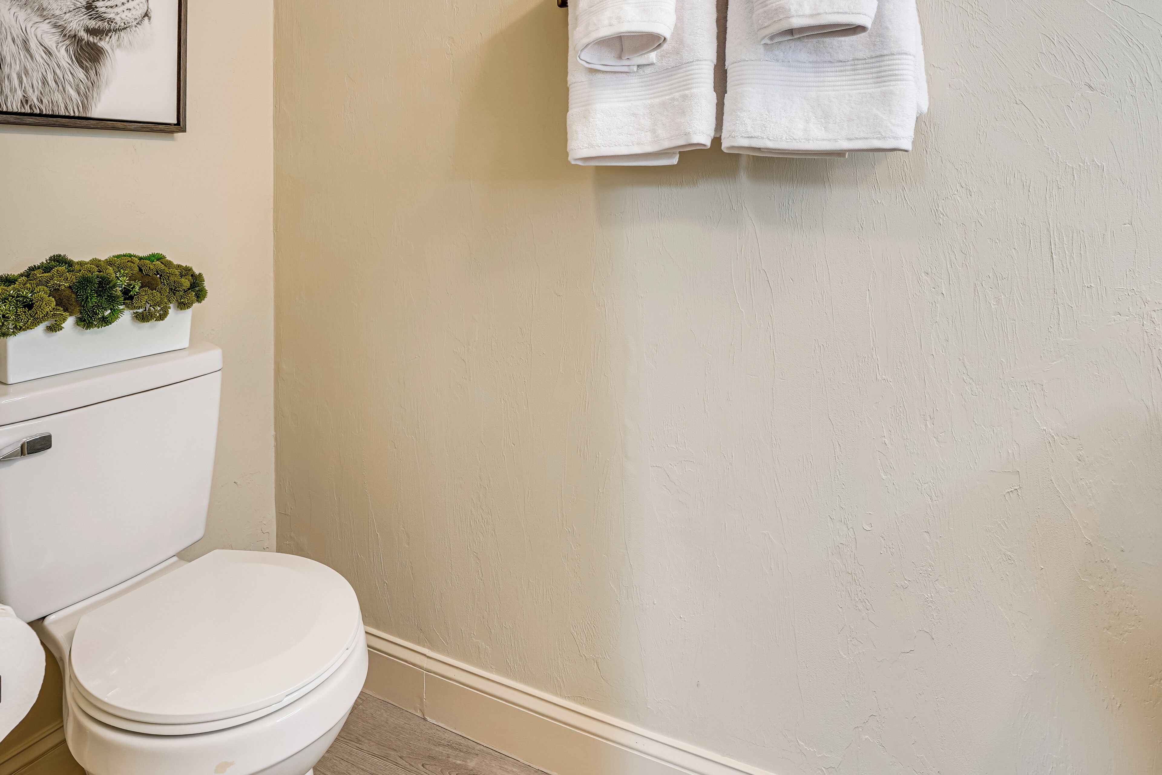 A bathroom with a toilet, a white sink, and a wall-mounted towel rack with two white towels.