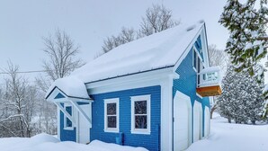 A blue house with a snow-covered roof and a garage door. - Vermont Retreat w/ Hot Tub: Romantic Getaway (Rochester)