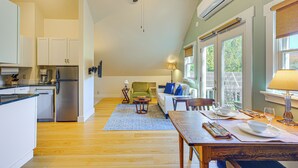 A spacious kitchen with modern appliances, a dining area with a wooden table set for two, and a cozy seating area with a green armchair and a white sofa. - Vermont Retreat w/ Hot Tub: Romantic Getaway (Rochester)