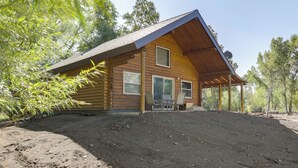Une cabane en bois avec un toit à deux versants, une véranda et un coin repas comprenant des chaises et une table.
