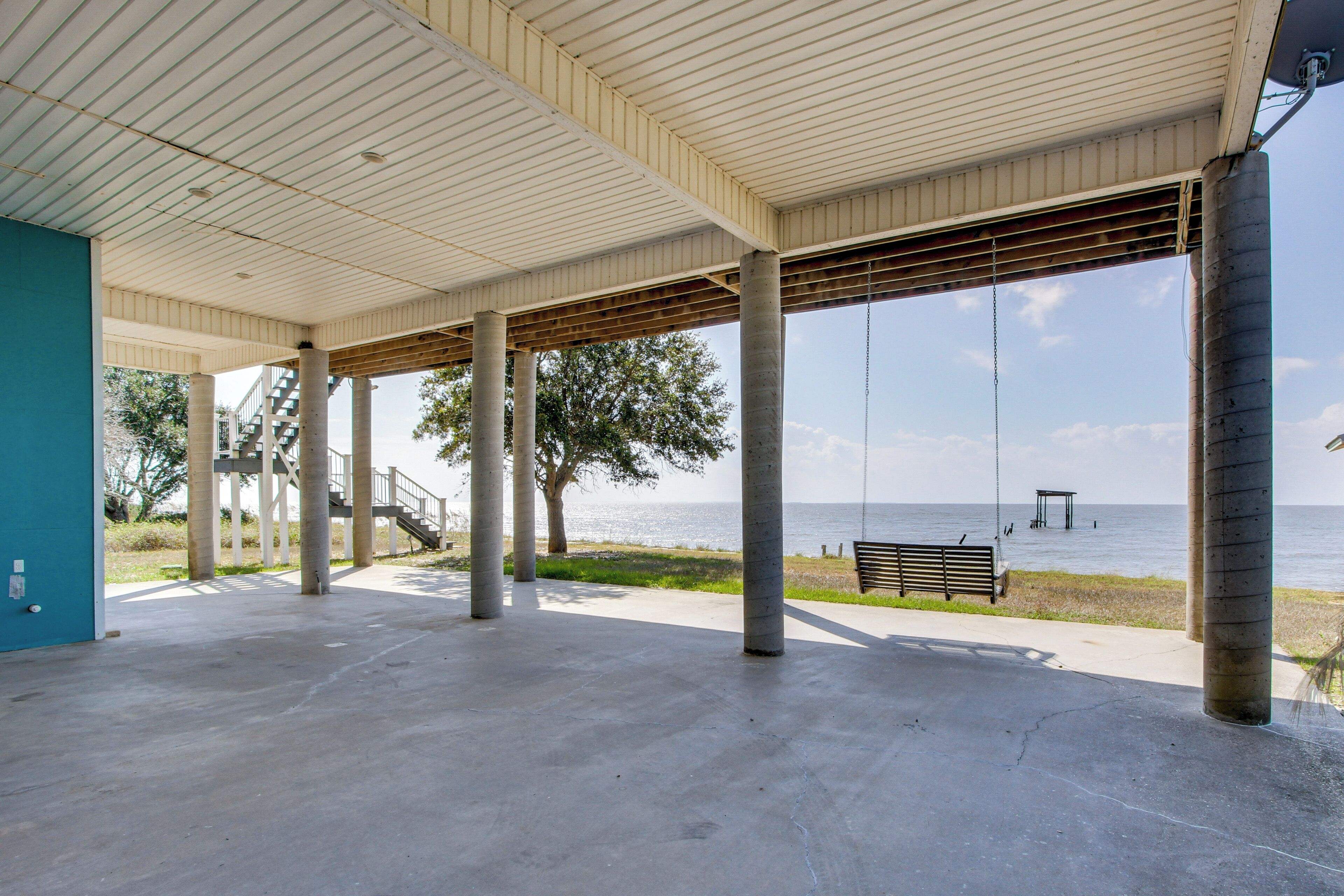 A covered outdoor area with concrete pillars, a bench, and a view of the water.
