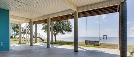 A covered outdoor area with concrete pillars, a bench, and a view of the water.