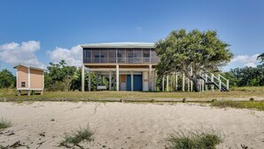 A two-story beach house with a balcony, a small adjacent shed, and a staircase leading to the upper level. - Private Beach & Views! Stilted Ocean Springs Home (Ocean Springs)