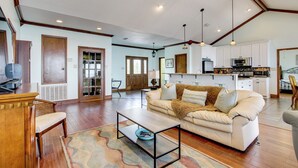 A spacious living room with a sofa, coffee table, and a kitchen area in the background. - Private Beach & Views! Stilted Ocean Springs Home (Ocean Springs)