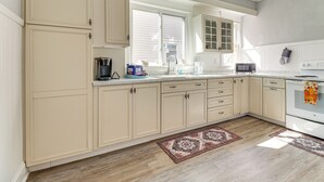 A kitchen with beige cabinets, a microwave, a stove, and a window with blinds. - 1 Mi to Dtwn & Franciscan University: Home w/ Yard (Steubenville)