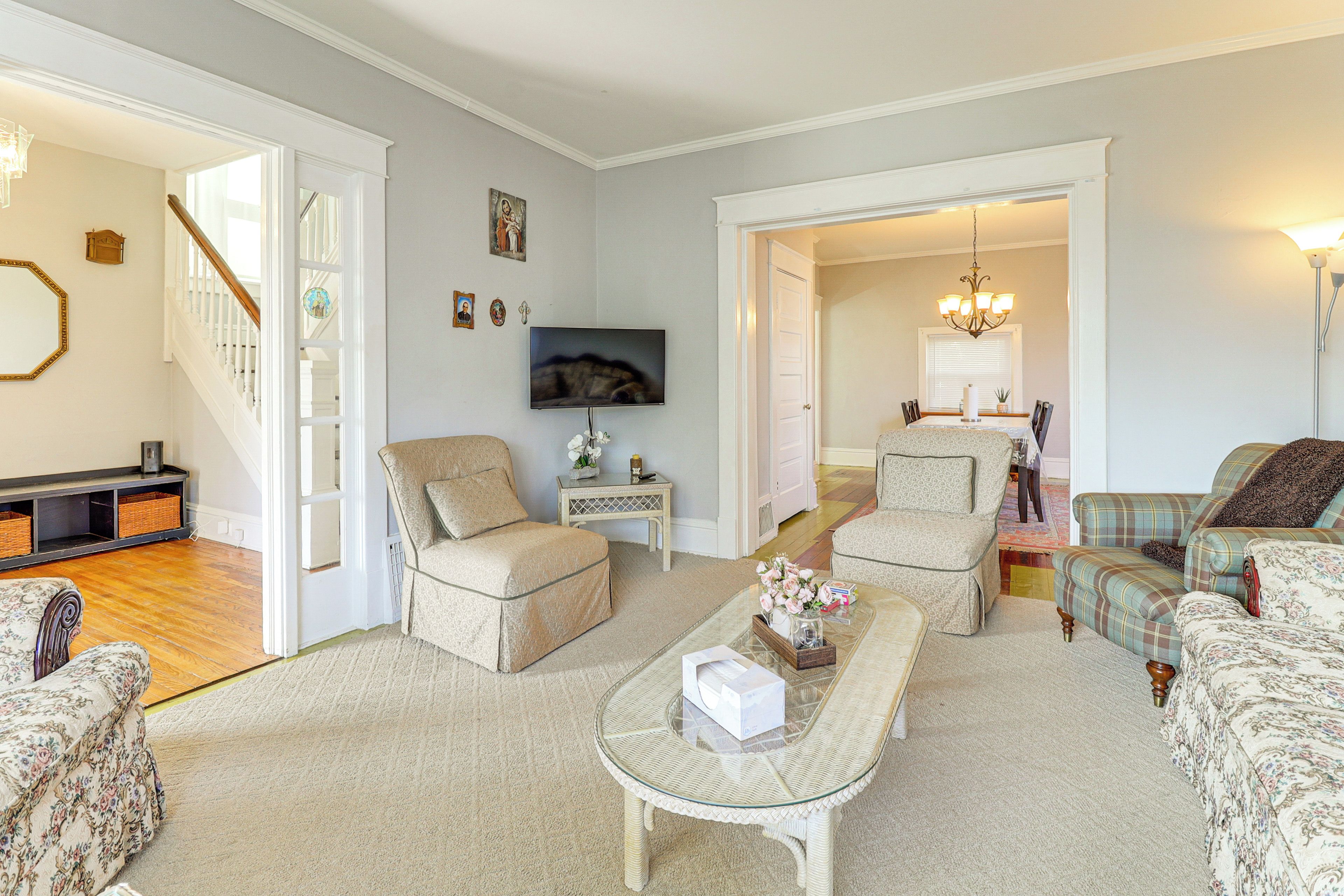 A spacious living room with a sofa, armchairs, a coffee table, and a television.