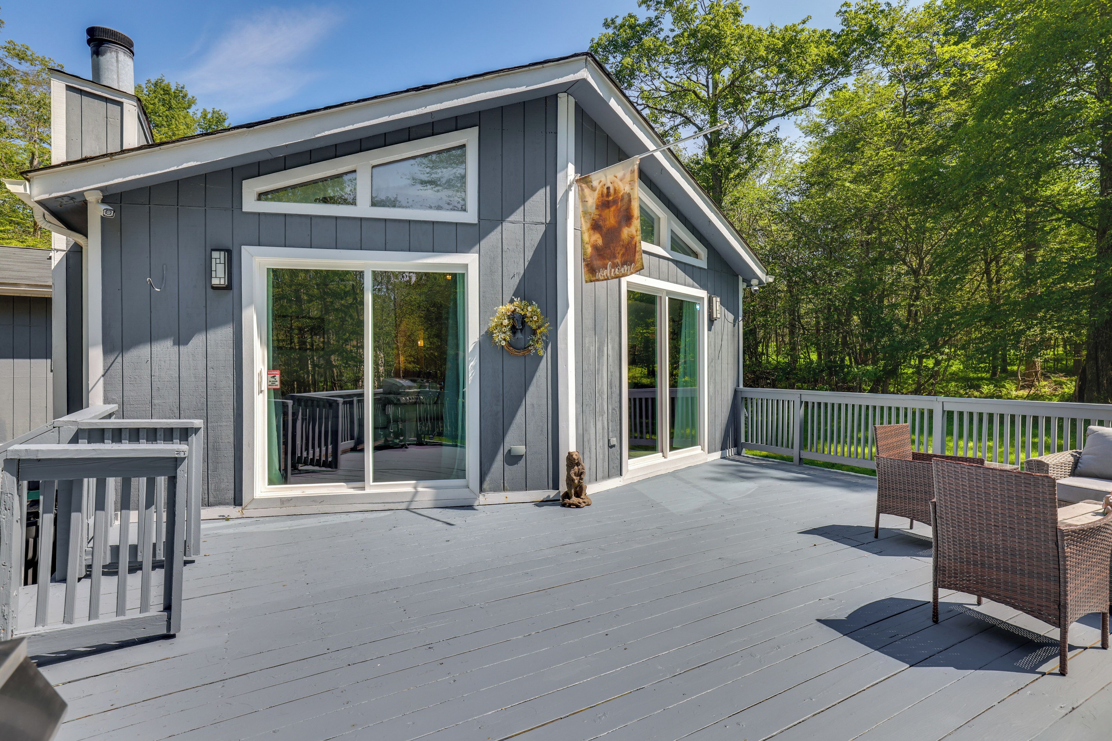 A gray house with a deck, a wreath, and a bear flag.