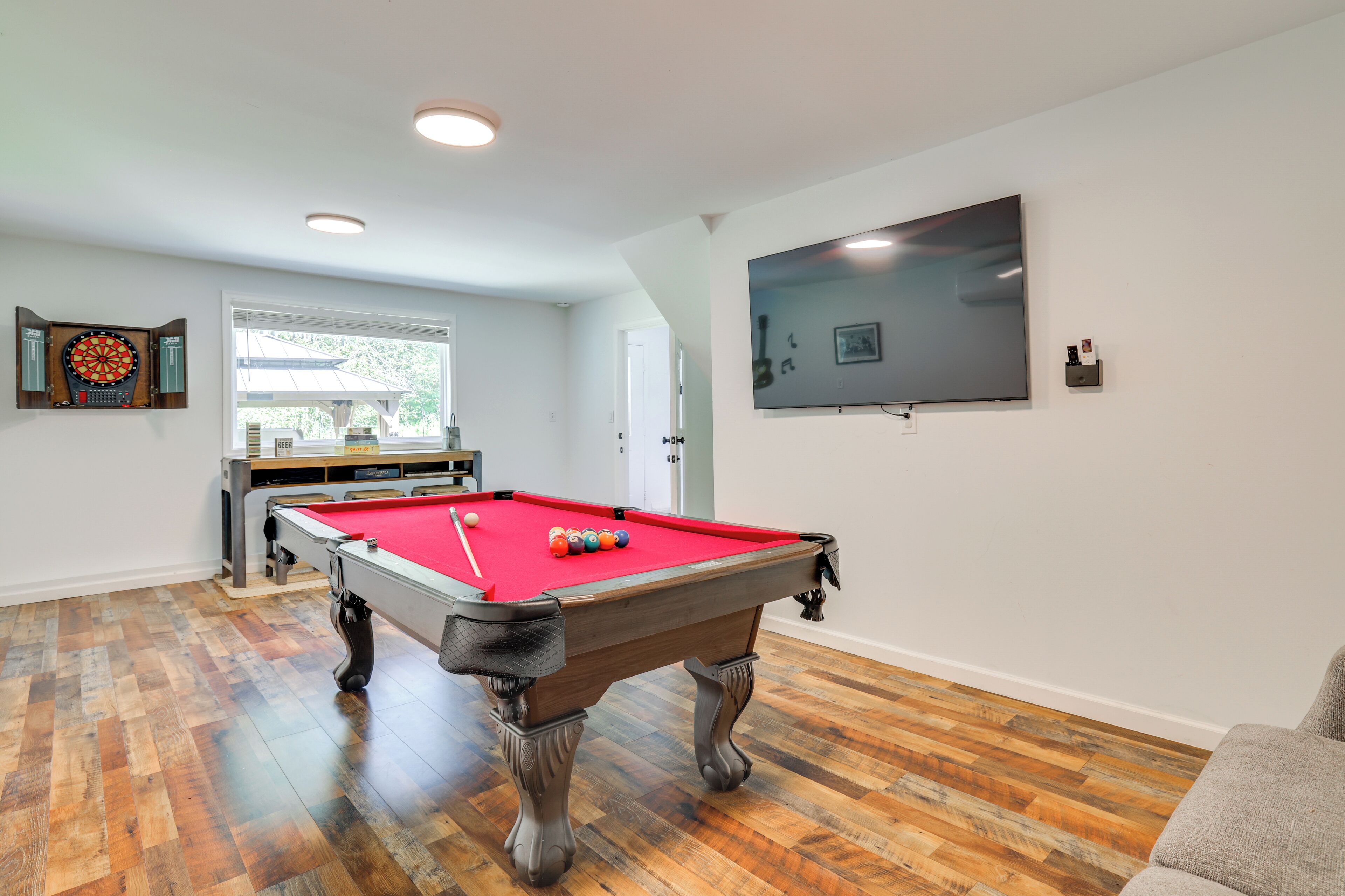 Una mesa de billar con bolas, un dardo y un televisor en la pared.