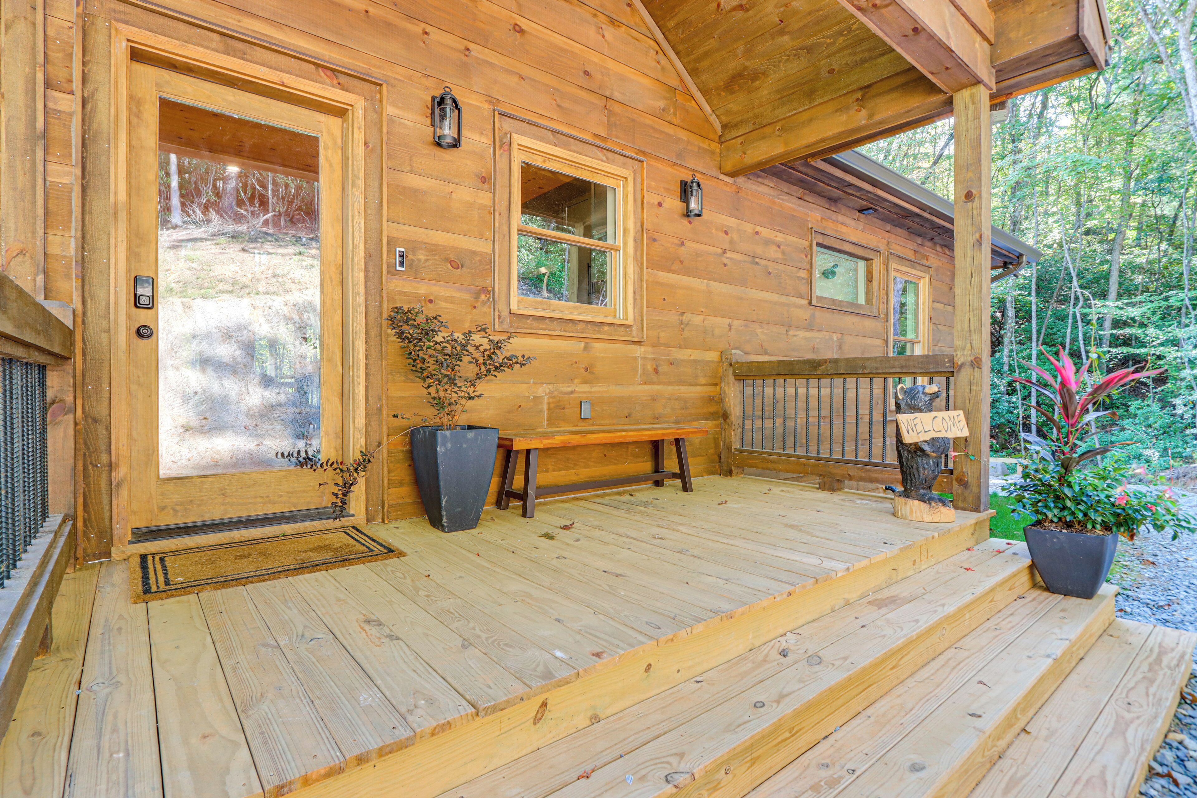 Une cabane en bois avec une véranda, un banc et une pancarte de bienvenue.