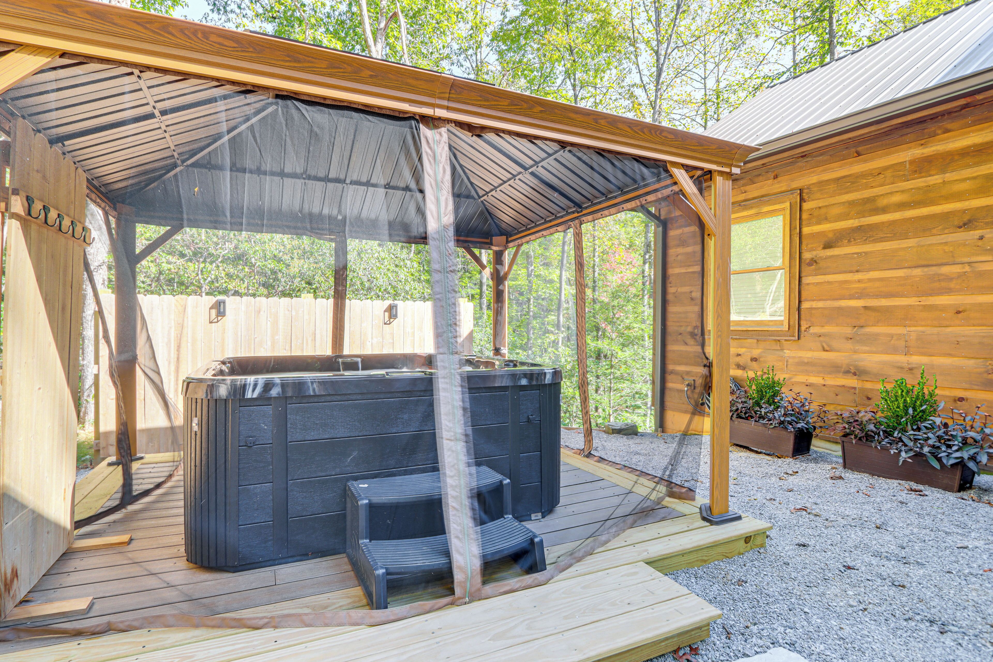 Een houten terras met een jacuzzi en trappen, een overdekt gebied met een metalen dak en houten wanden.
