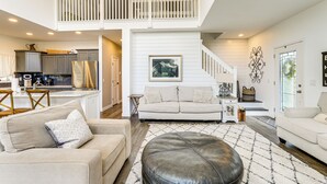 A spacious living area with a high ceiling, a staircase, and a kitchen in the background. - Lake Wawasee Family Getaway in Syracuse! (Syracuse)