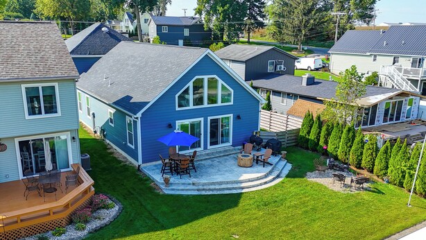 A residential property with a large deck, a covered patio, and a well-maintained lawn. - Lake Wawasee Family Getaway in Syracuse! (Syracuse)