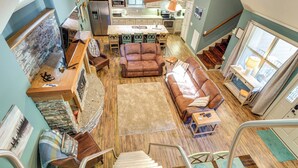 A spacious living area with a fireplace, a dining table set for four, and a kitchen in the background. - 'tookies Retreat' Walk to Mairina! Home w/ Hot Tub (Smithville)