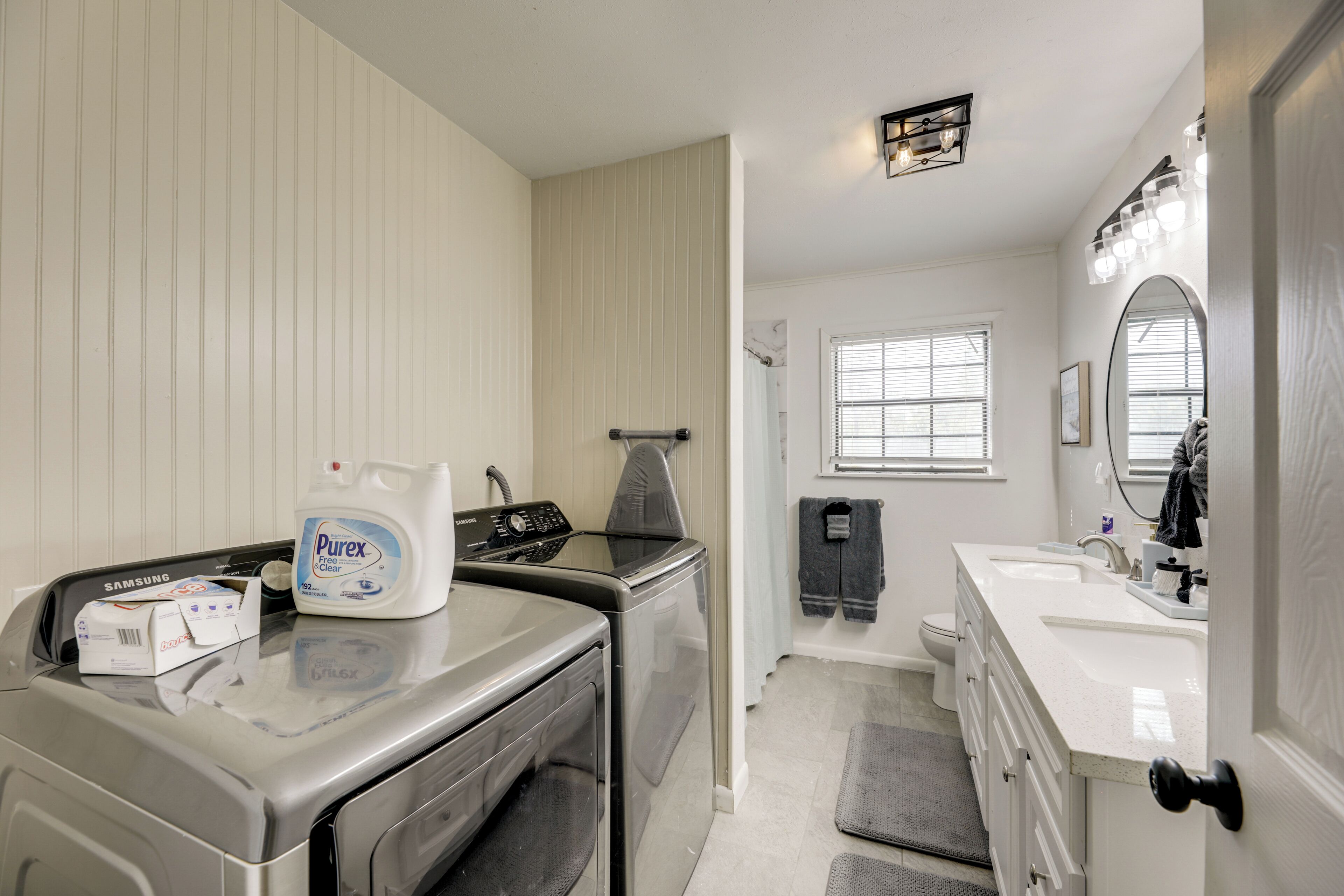 A laundry area with a washing machine, a dryer, and a bottle of Purex Clear detergent.