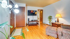 A living room with wooden flooring, a television, a lamp, and a patterned sofa. - Walk to Parks & Greenway: Sioux Falls Getaway! (Sioux Falls)