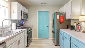 A kitchen with white cabinets, a blue door, stainless steel appliances, and a red fire extinguisher. - 7 Mi to the Hammocks Beach: 3 BD Near Camp Lejeune (Hubert)